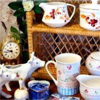 Different styles of porcelain dishes for example cow-themed milk pitchers, sugar bowls, and a mug