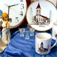Toholampi-themed decorative plate and mugs, and also a pair of small glass angels, a couple of angel statues, and two clocks