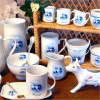 Toholampi-themed porcelain dishes such as milk pitchers, mugs, bowls, pitchers, sugar bowls and a plate