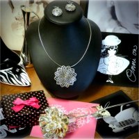 A necklace, earrings, a metal rose, postcards, and shoe-shaped bottle stand